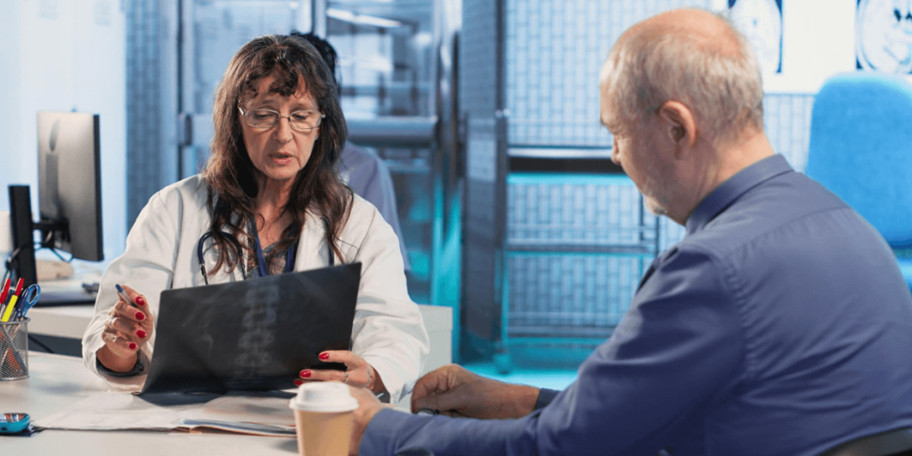 Doctor reviewing an X-ray with an elderly patient in a clinic, explaining results and discussing medical condition.